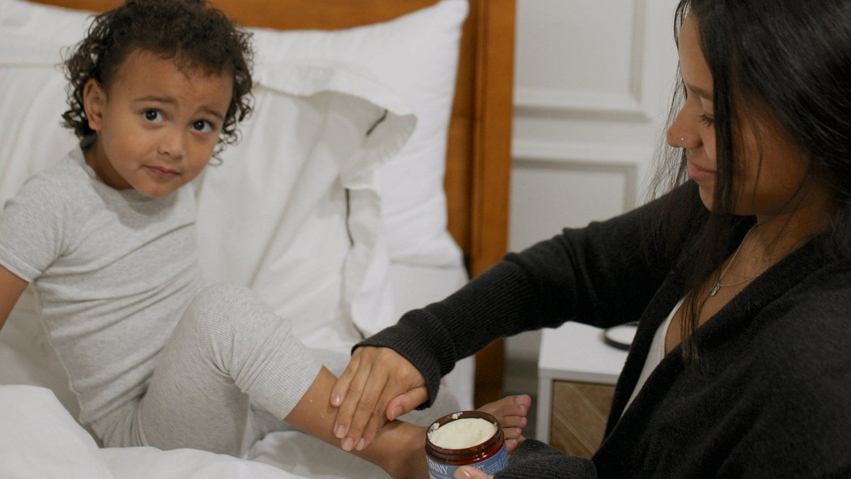 Mom massaging her toddler's feet in bed at bedtime