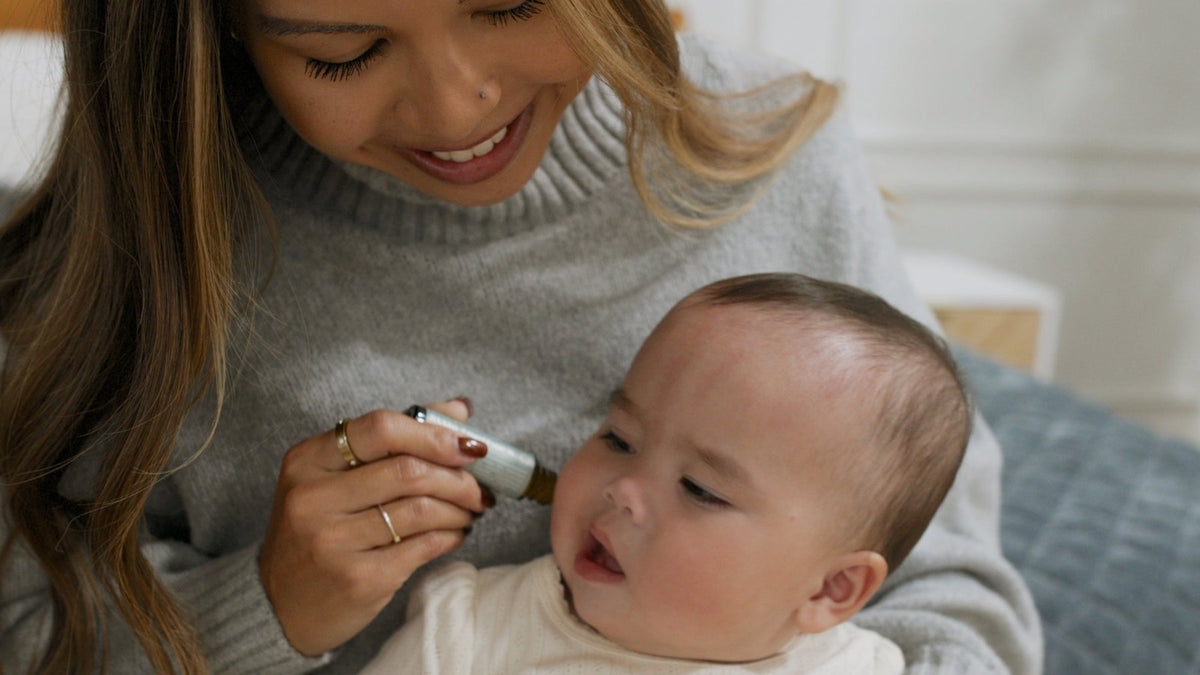 Mom smiling as she rolls Little Teethers along her baby's cheek