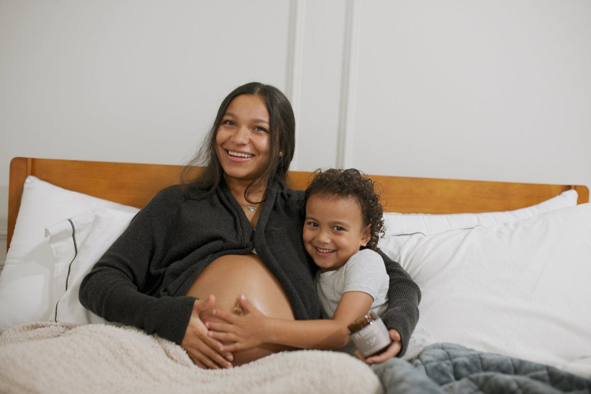 Smiling baby lying on a bed while mom watches