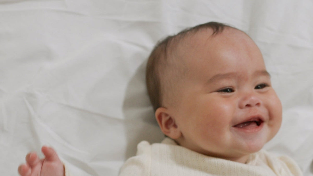 Laughing baby lying on a white bed