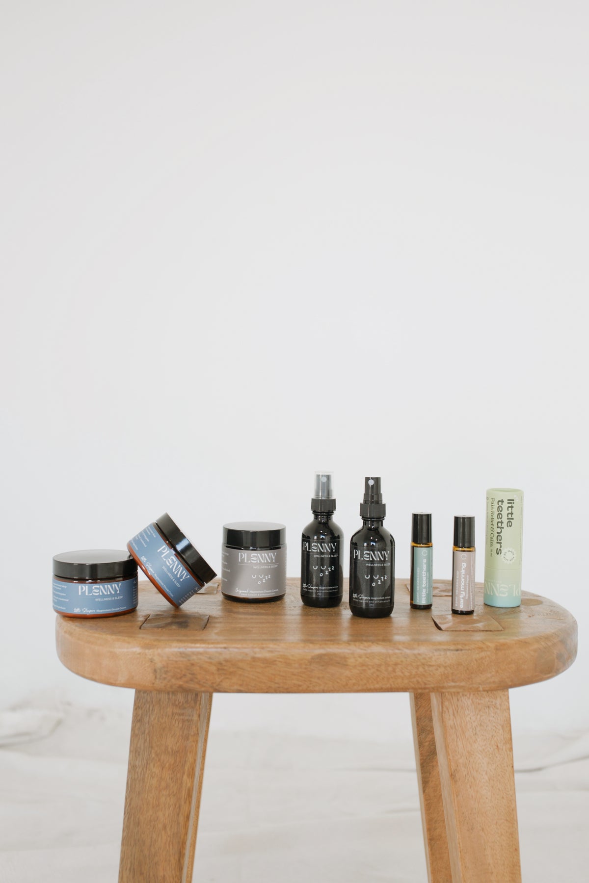 Plenny sleep serums, Dream Creams and rollers lined up on a wooden stool