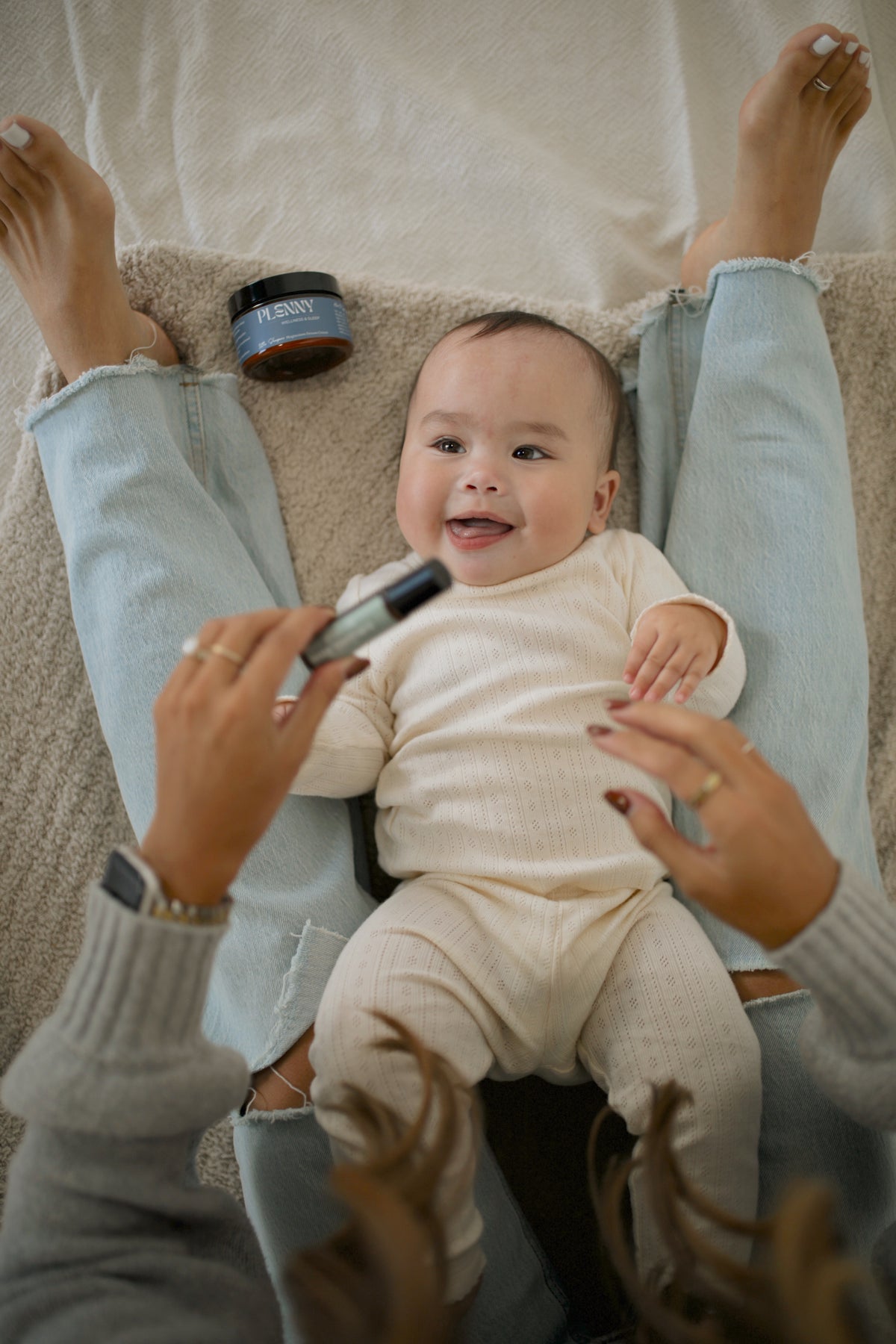 Smiling baby lying on a blanket while mom rolls on Little Teethers