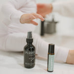Little Sleepers magnesium spray and Little Teethers roller on a white surface beside a baby