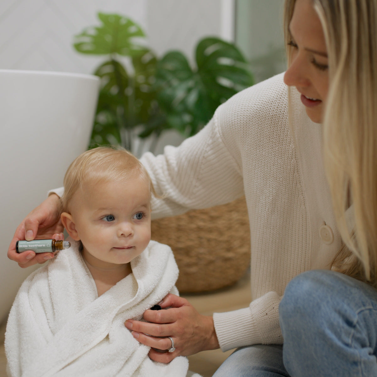 Mom applying Little Teethers roller to her baby's cheek after bath